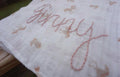 Embroidered fabric with 'Happy' text and animal patterns on a wooden surface