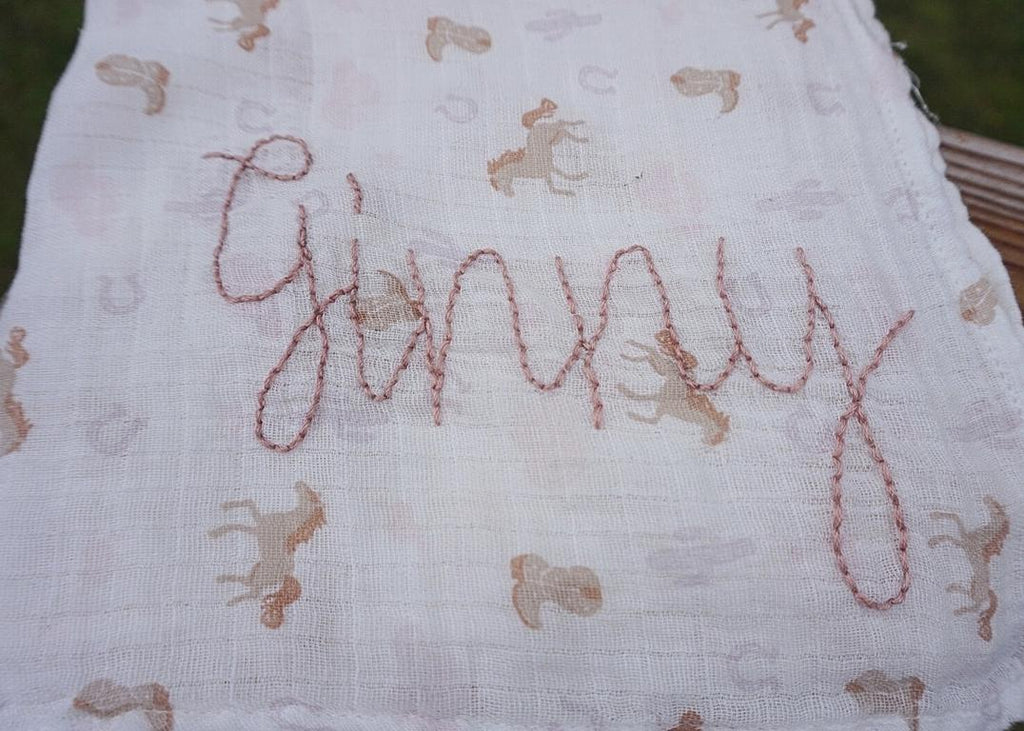 Textile with embroidered pattern and 'Ginny' text on a white background