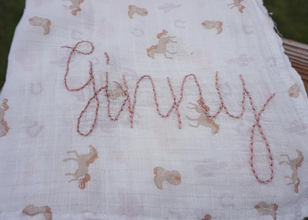 Textile with embroidered pattern and 'Ginny' text on a white background