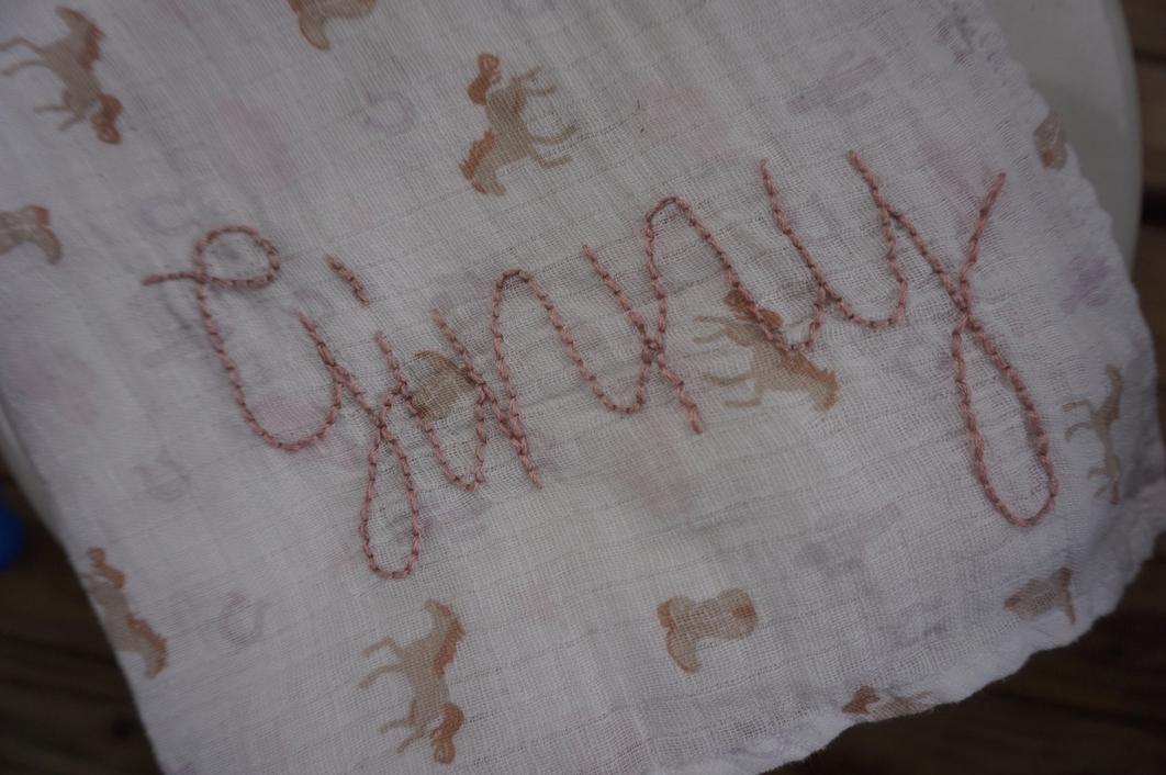 Textile with embroidered name and horse patterns