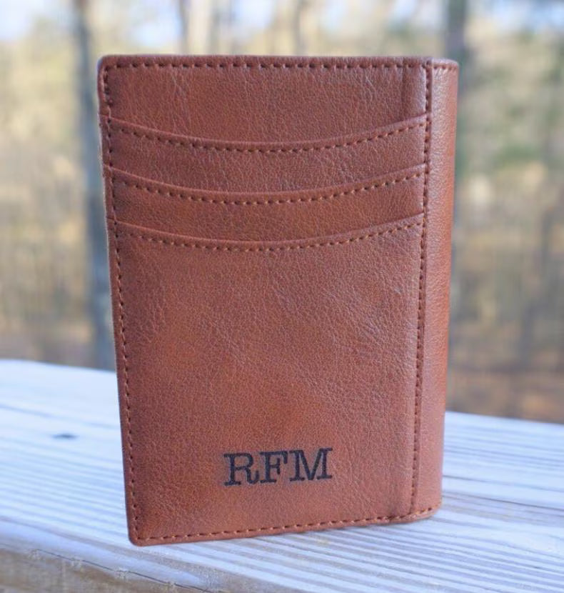 Brown leather wallet with 'RFM' initials on a reflective surface